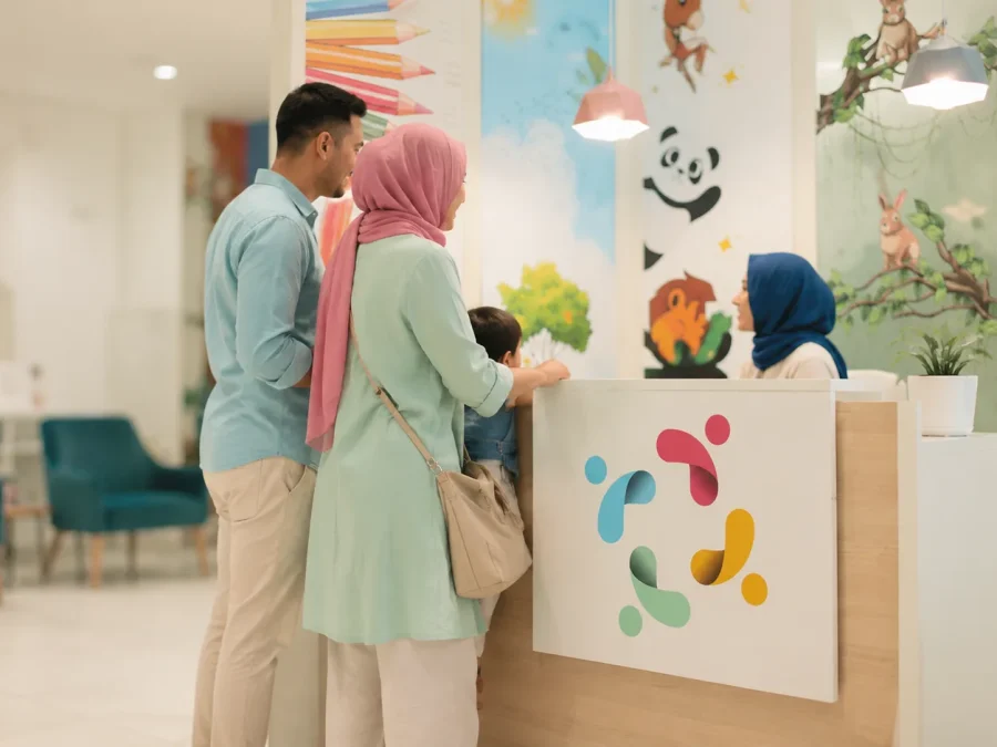 Une famille avec son enfant accueillie au comptoir de réception du centre Kids Care à Marrakech, devant une fresque murale illustrée d’animaux